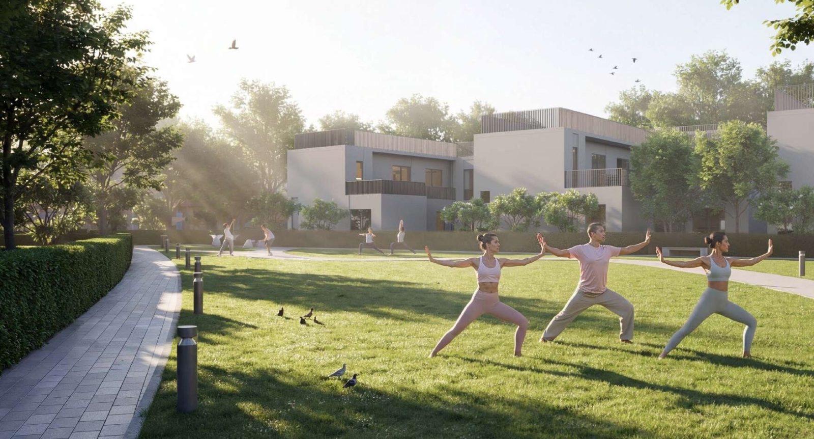 People practising yoga on a lawn at Sobha Sanctuary in morning light, with townhouses behind