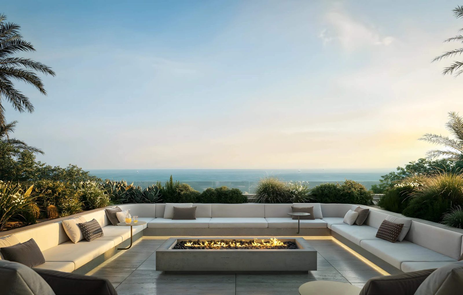 Sunken outdoor lounge at SOMA Residences with a long firepit, built-in seating and a sea view